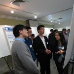 Three men and a women discussing in front of research poster